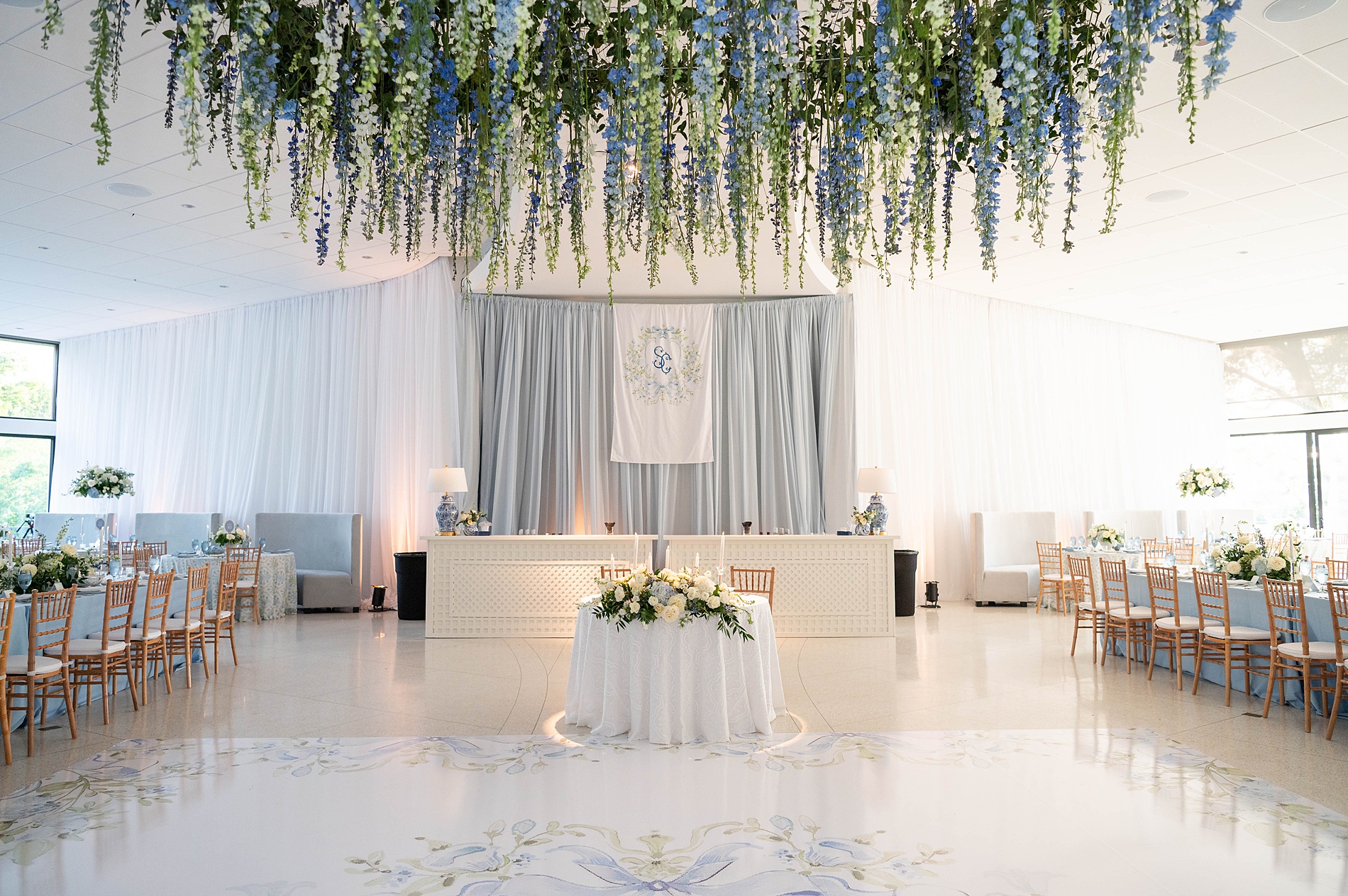 Spring wedding reception with green and blue florals hanging from ceiling