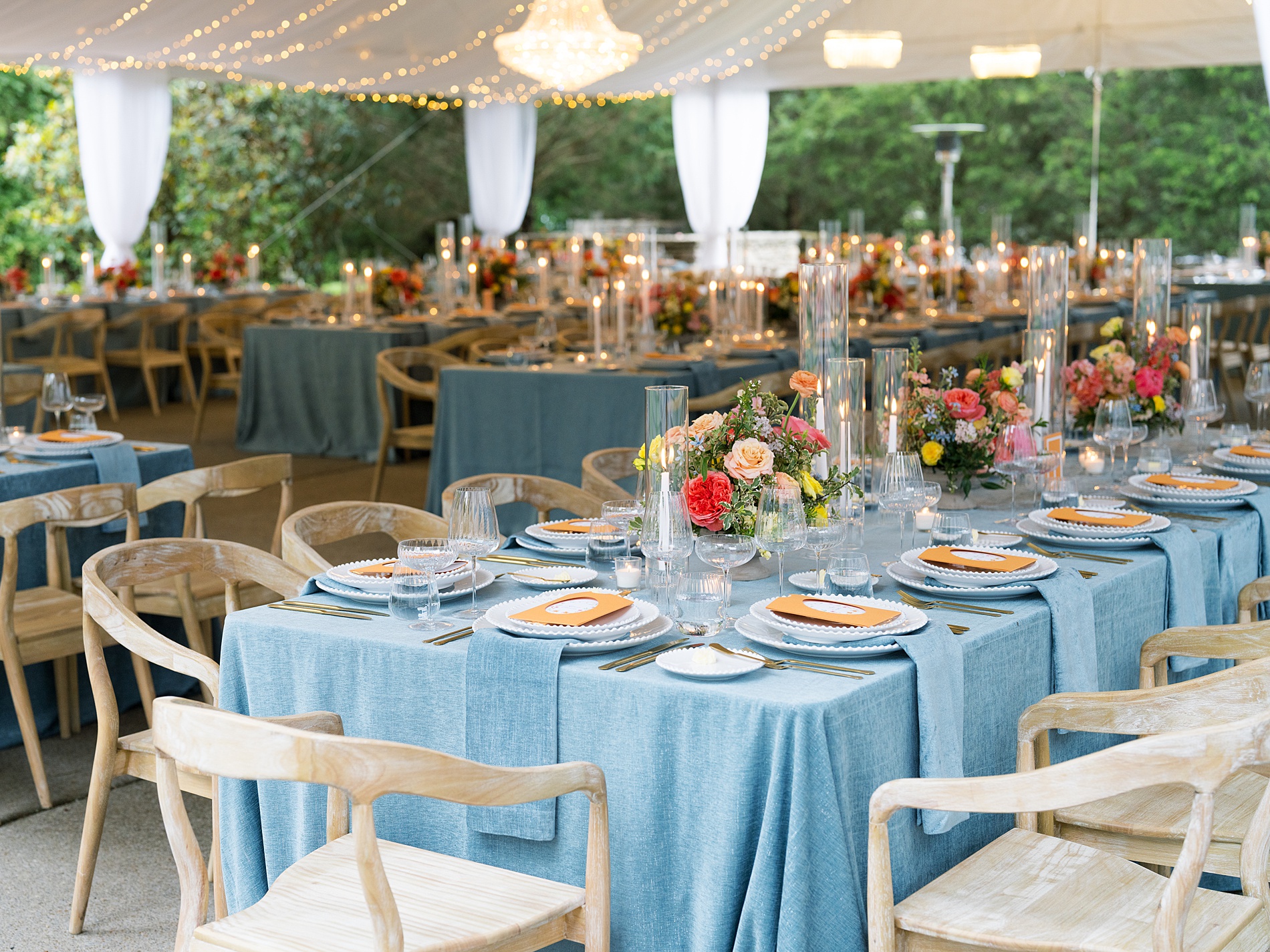 menus tucked into a custom die-cut orange pocket, featuring floral artwork. The menus and orange acrylic table numbers popped against the blue linens and tied into the colorful spring floral centerpieces. 