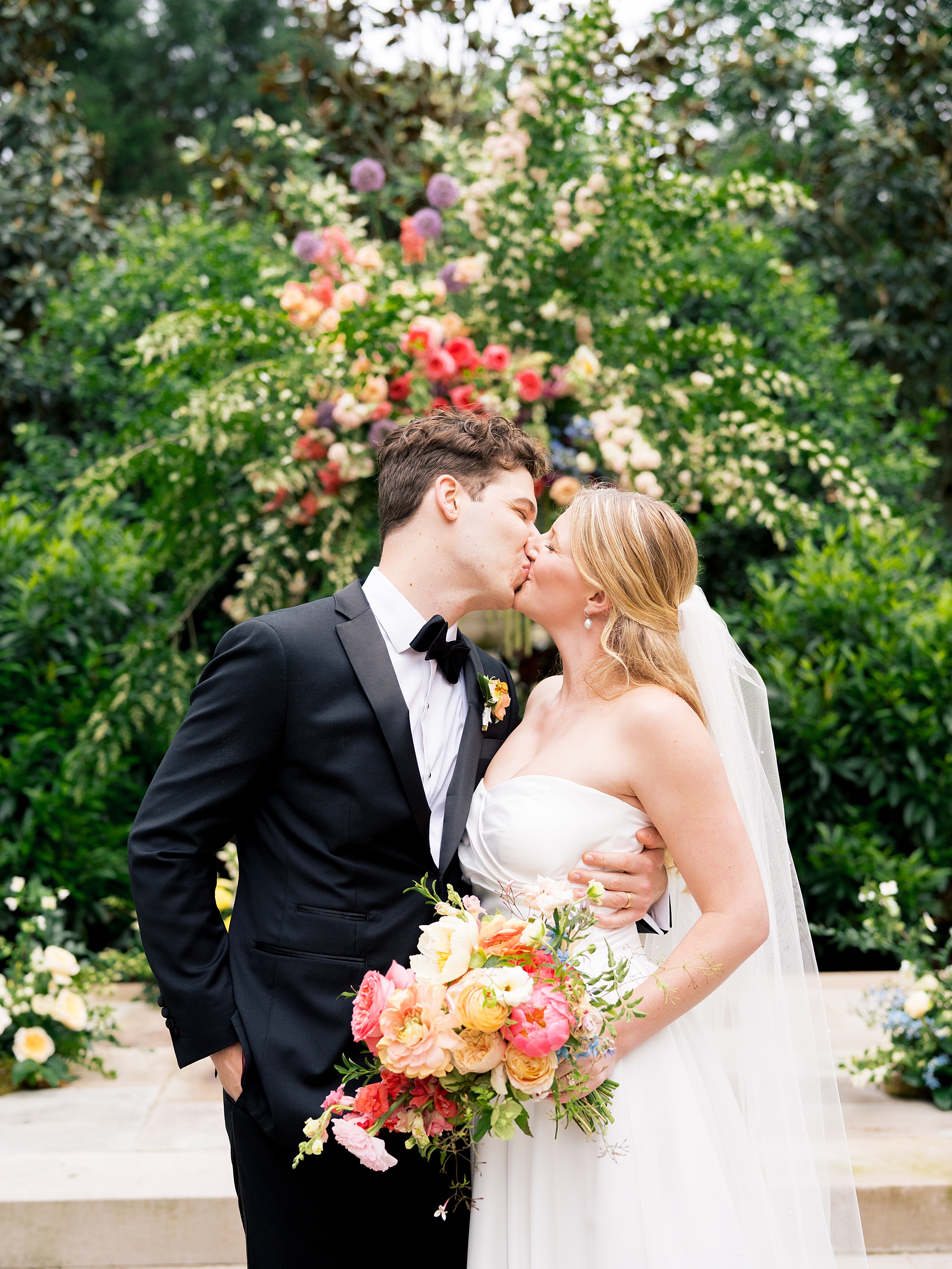 bride holding colorful wedding bouquet kisses her groom after Nashville wedding at Belle Meade