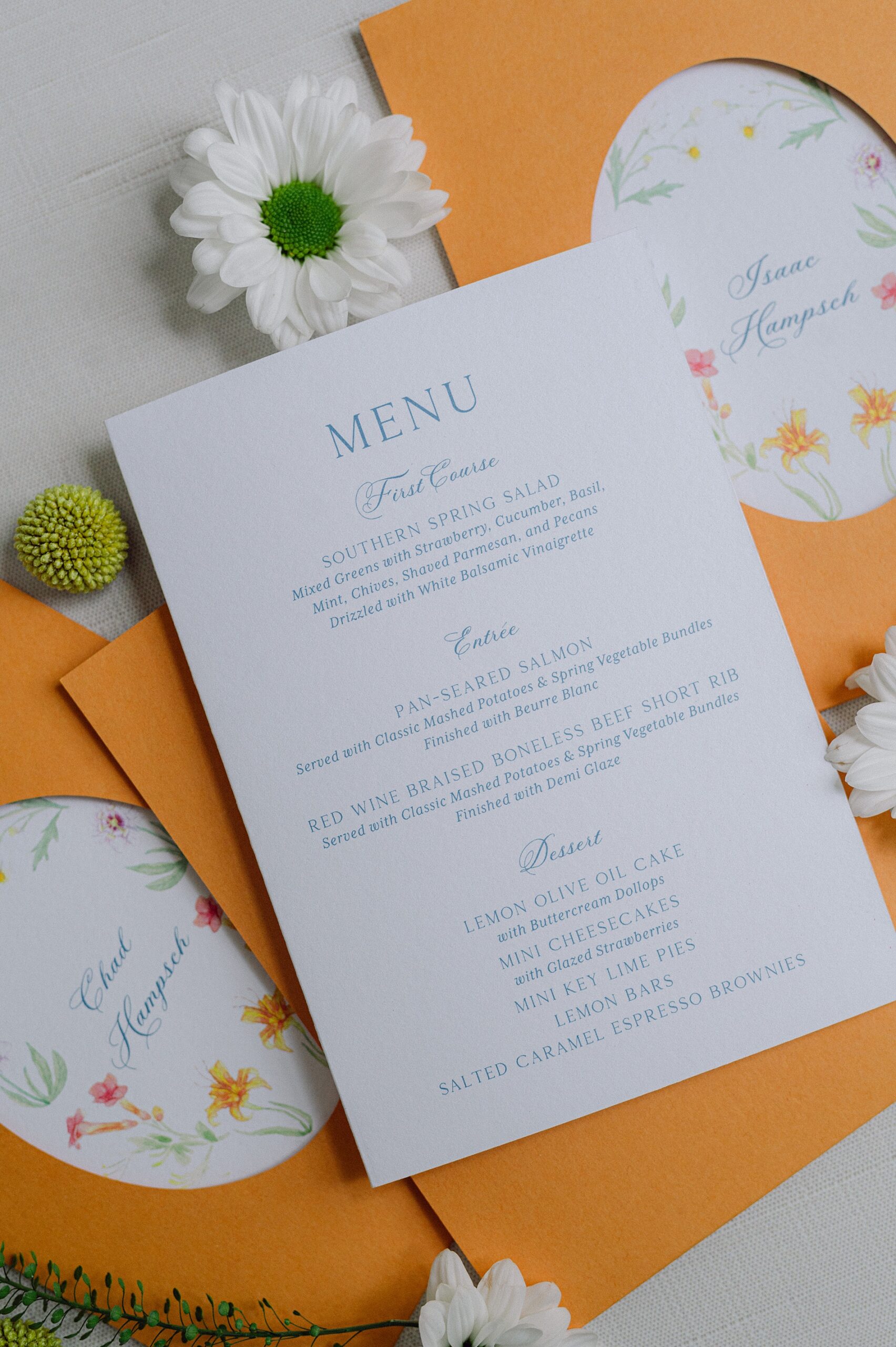 menus tucked into a custom die-cut orange pocket, featuring floral artwork by the groom 