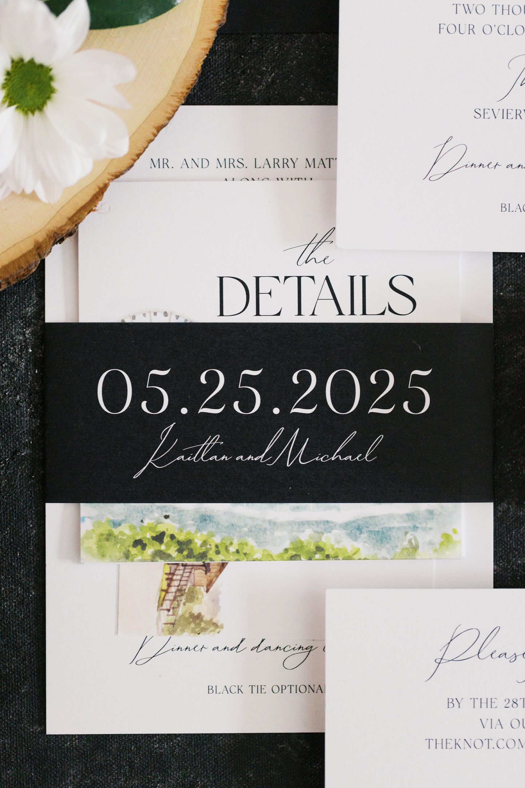 wedding invitation paper stack held together with black band featuring couple's name and wedding date in white calligraphy 
