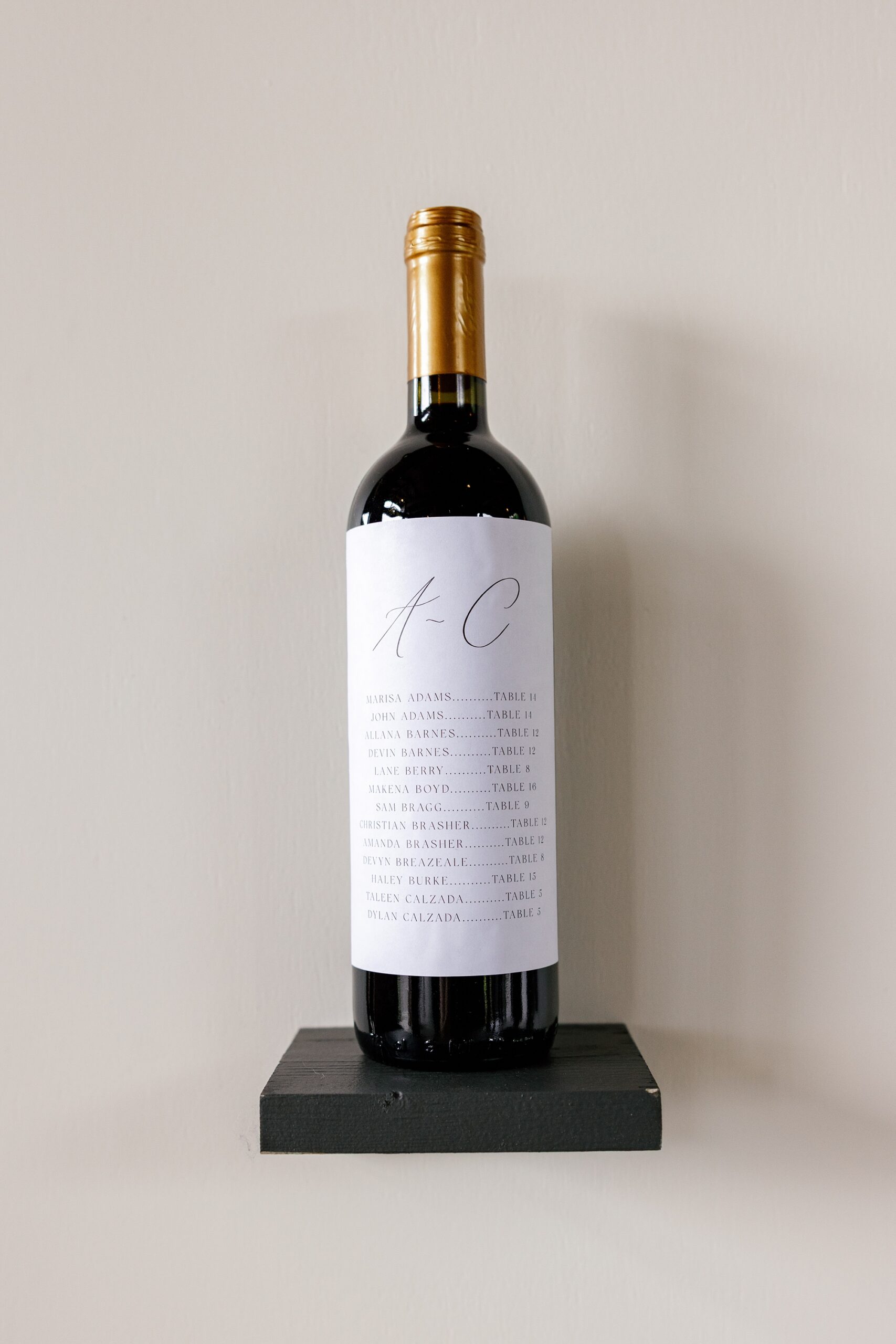 wine bottle with guests names on label assigning their table number at Timeless black and white wedding