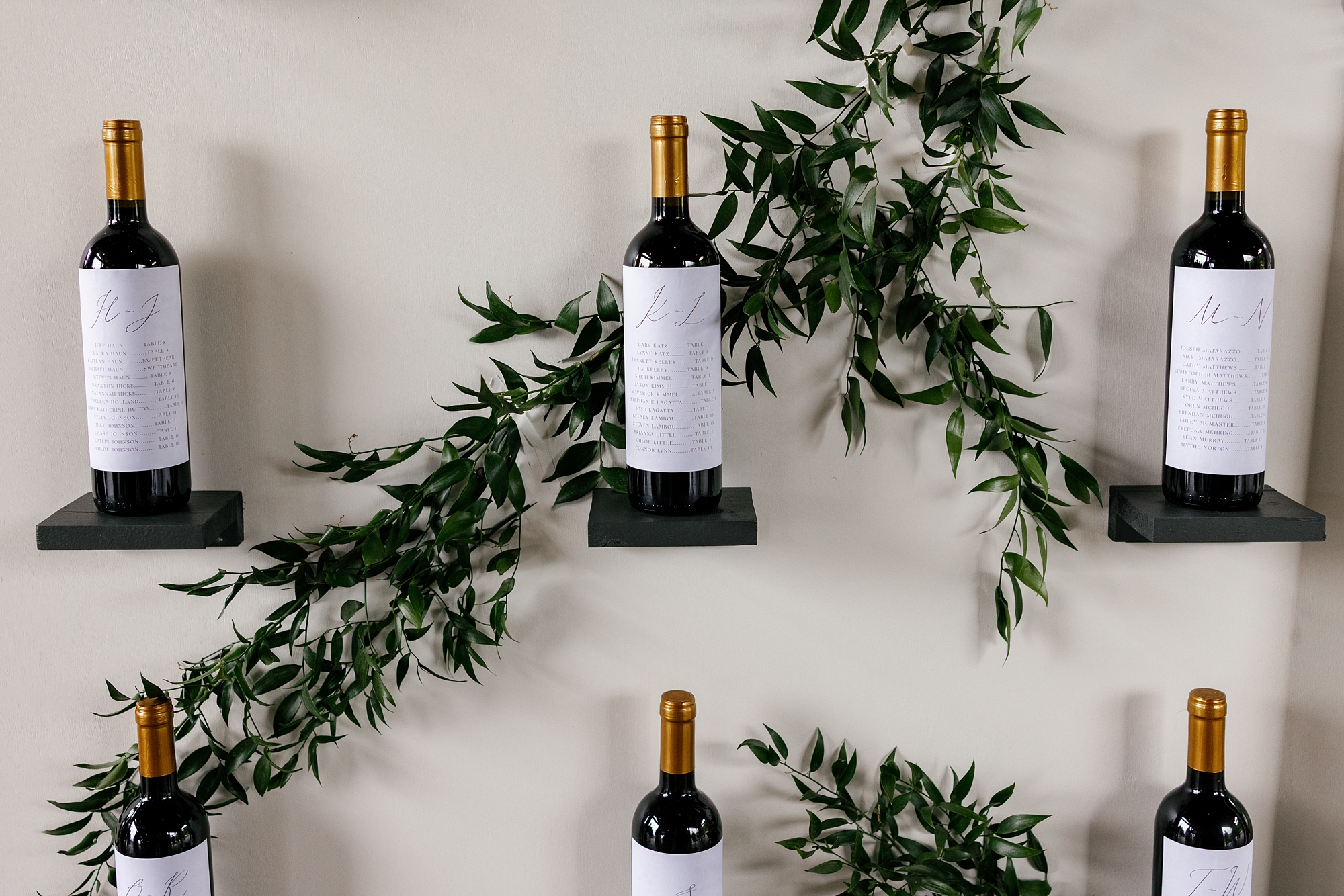 custom wine labels on wine bottles assign guests seats for this custom seating chart designed by full-service wedding design house