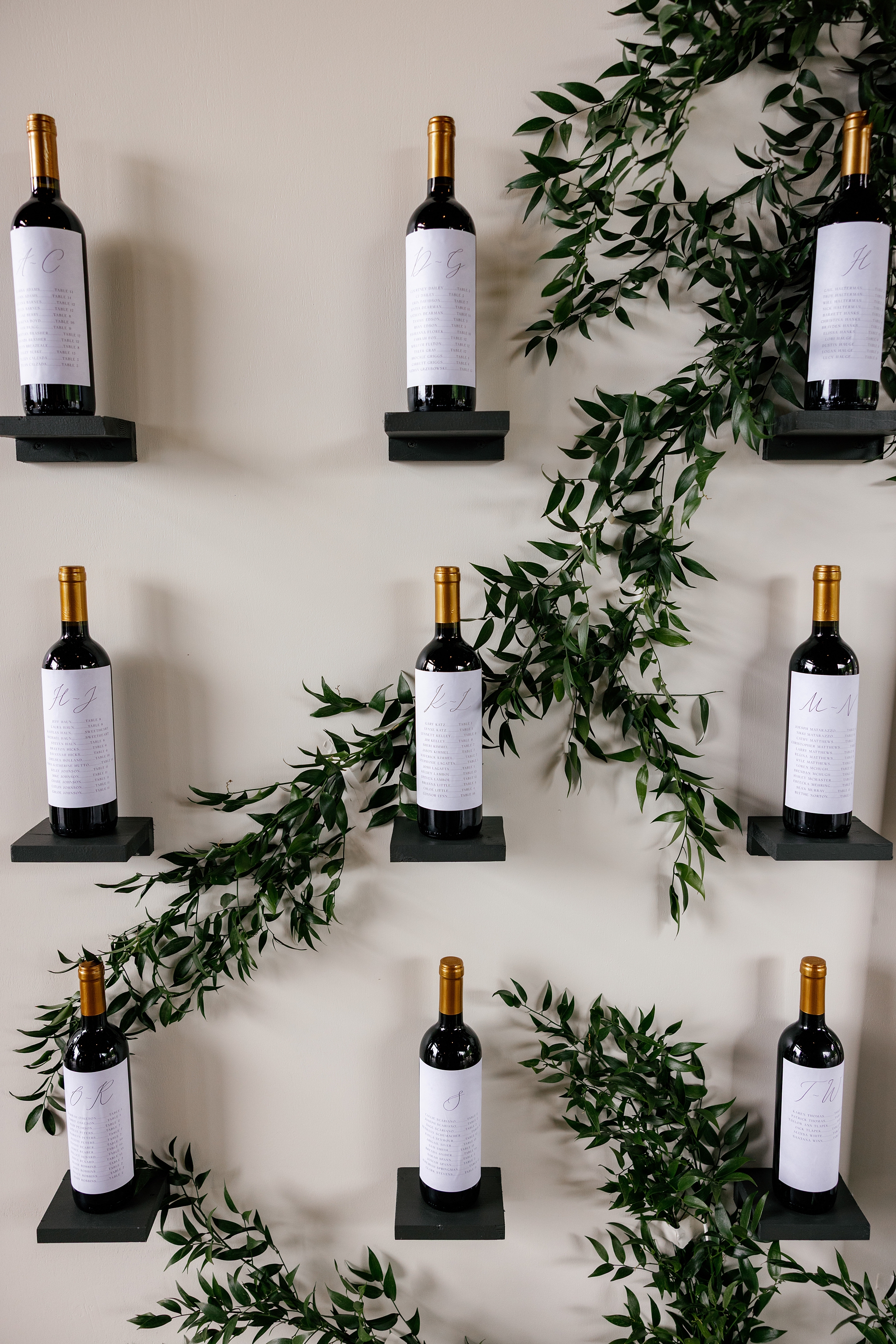 wine bottle seating chart with wine bottles on small black shelves 