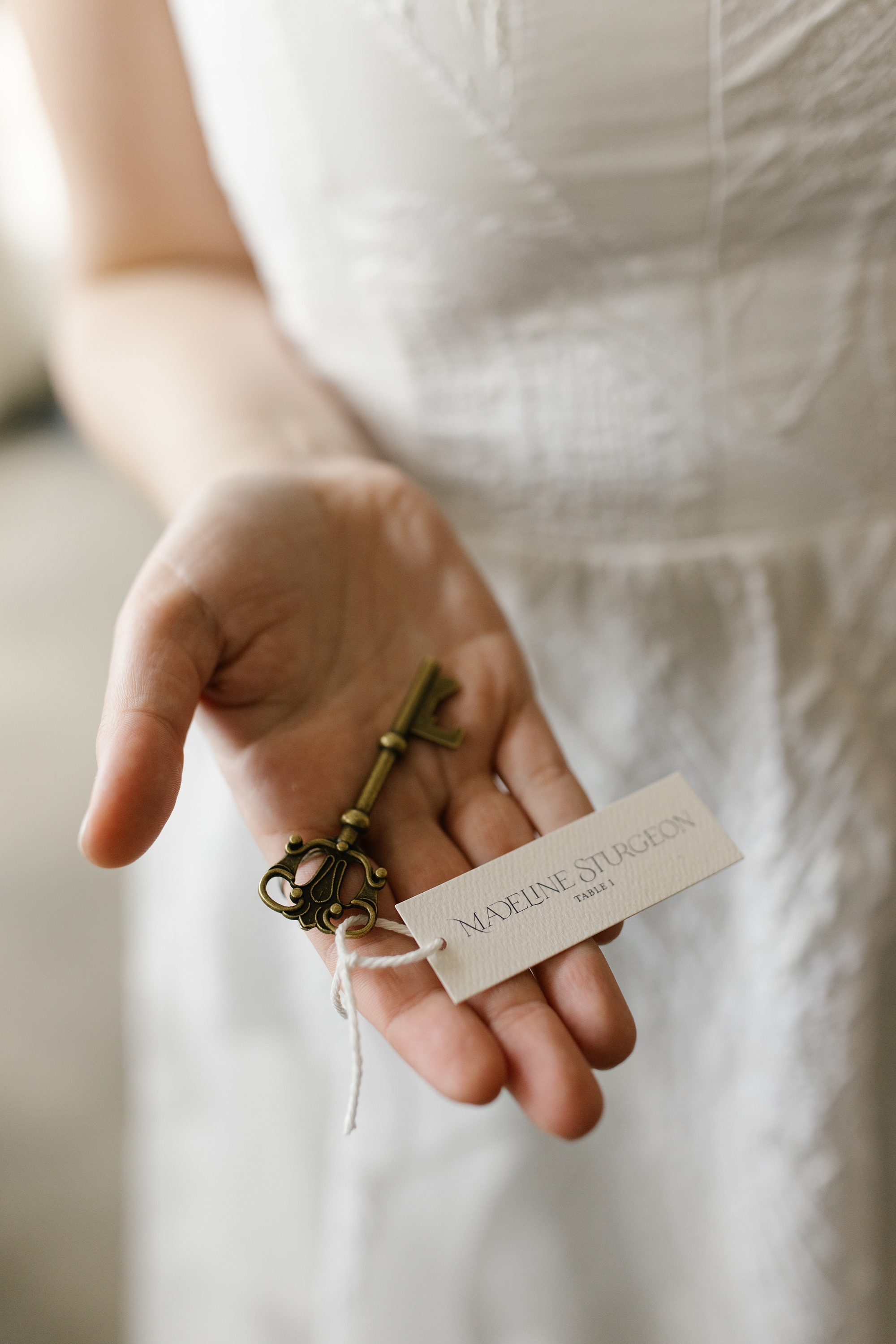 bride holds vintage key in hand with tag attached noting guest's name and table number