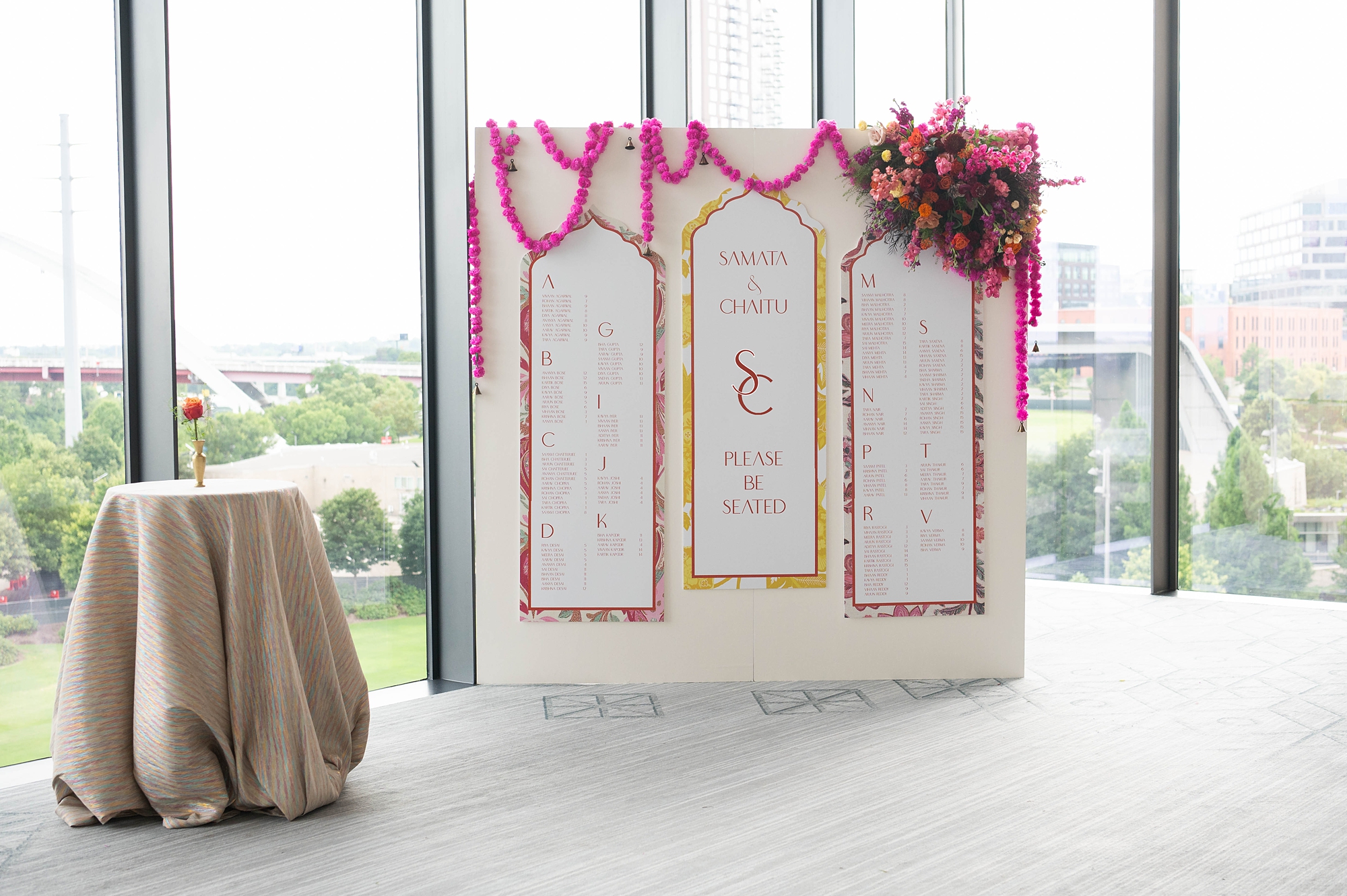 seating chart display decorated with pink garland and vibrant flowers