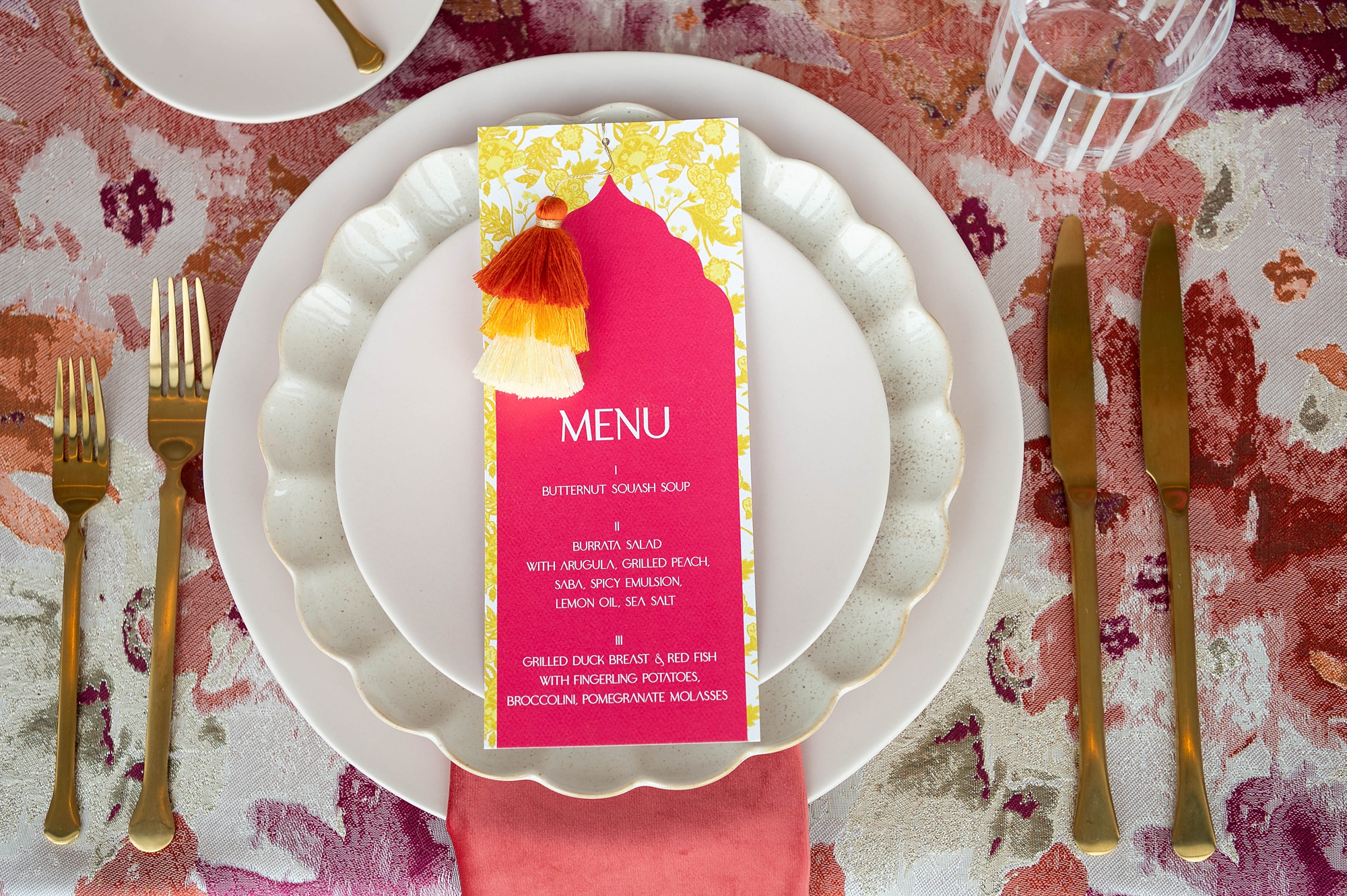 yellow patterned menu with a top layer of pink card stock and ombre pom poms
