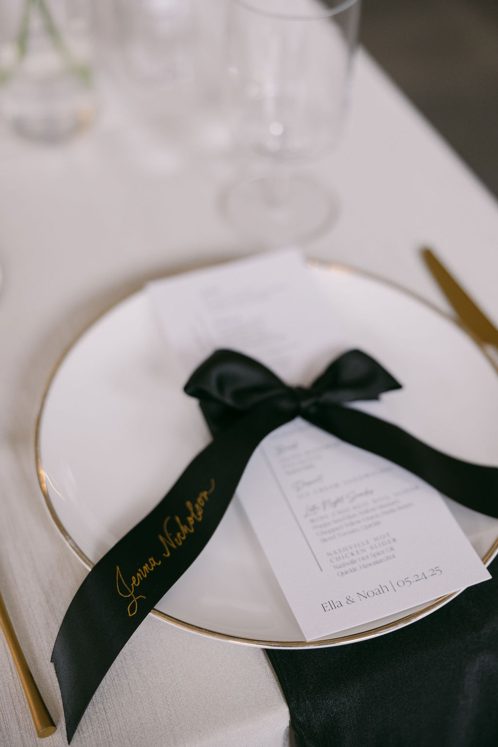 black satin ribbon place cards tied around white menus at place setting 