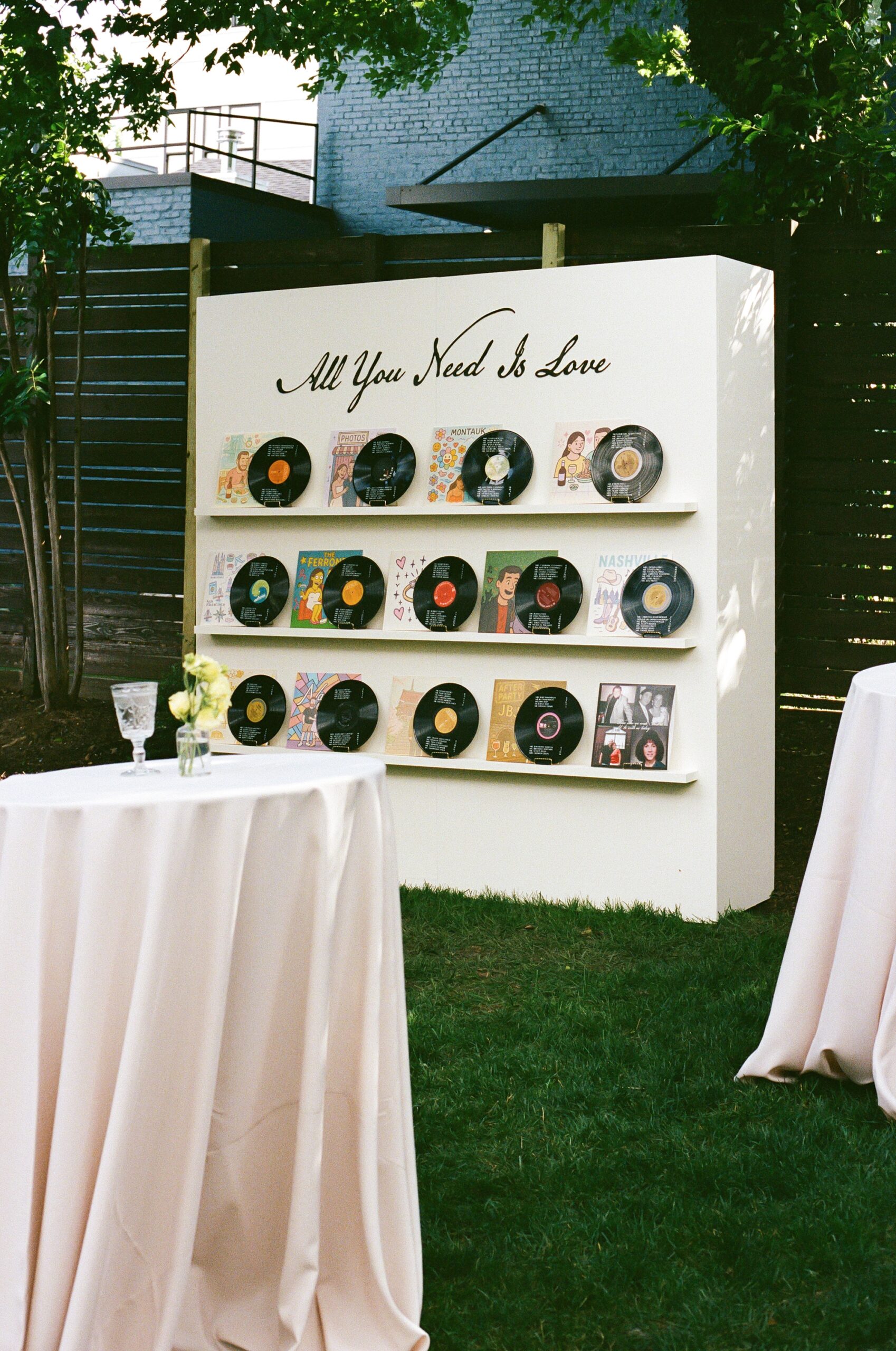 "All you need is love" written on seating chart display featuring vinyl records that list table number assignment 