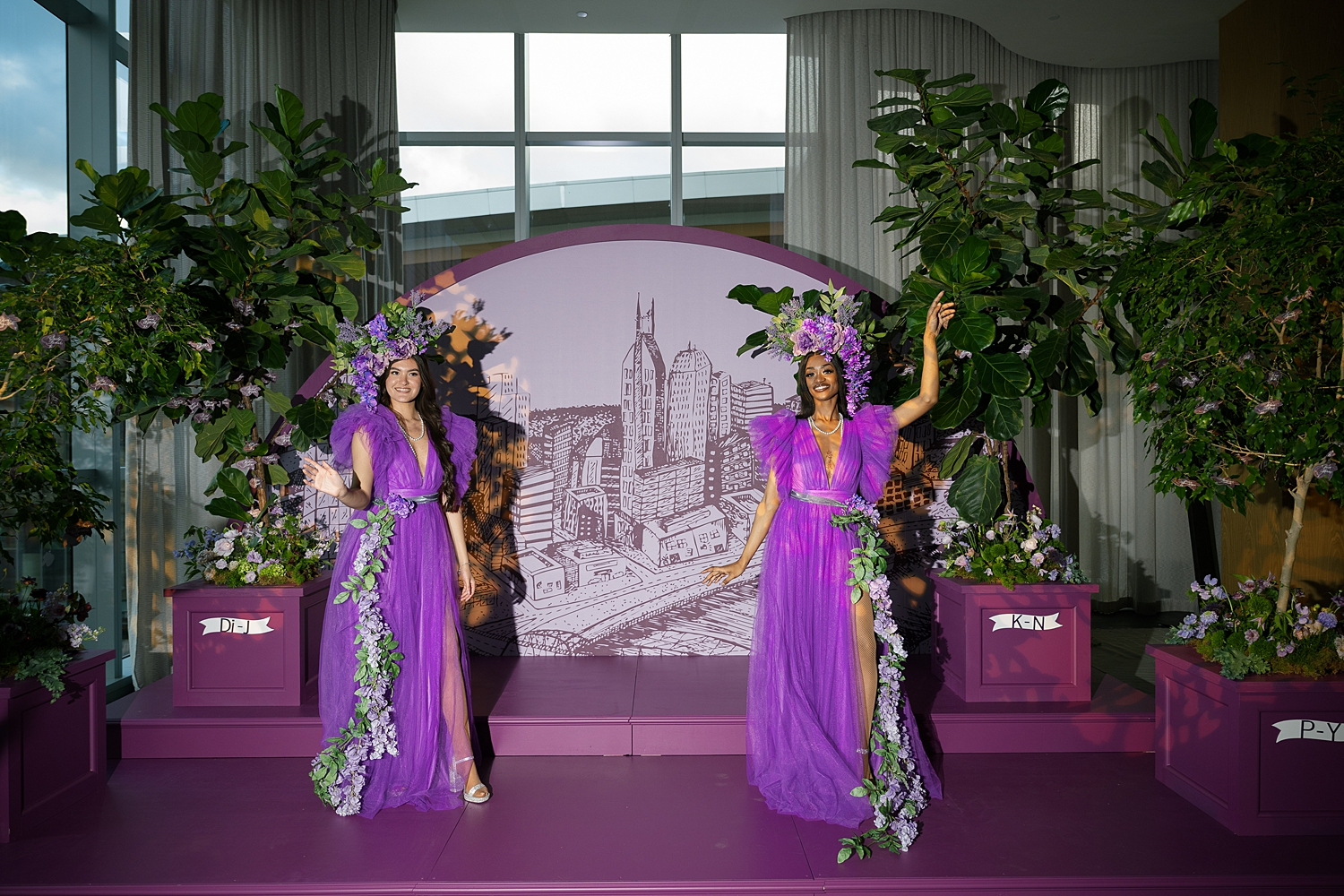 Seating chart installation with cityscape image framed by two trees holding escort cards shaped like figs 
