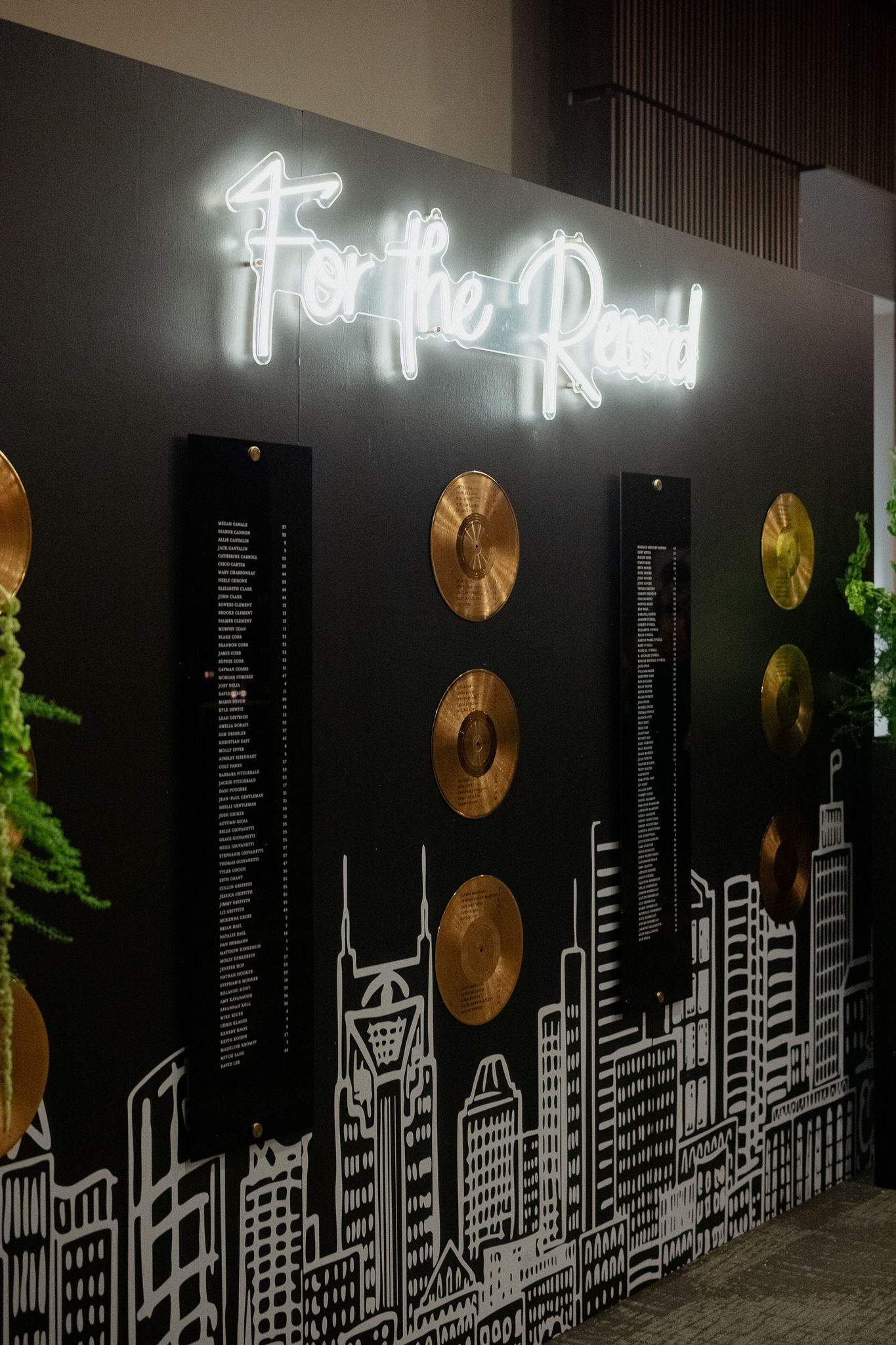 A music city seating chart featuring  Nashville skyline, neon sign, and gold vinyl records displaying seating arrangements for classic black and white wedding at Country Music Hall of Fame 