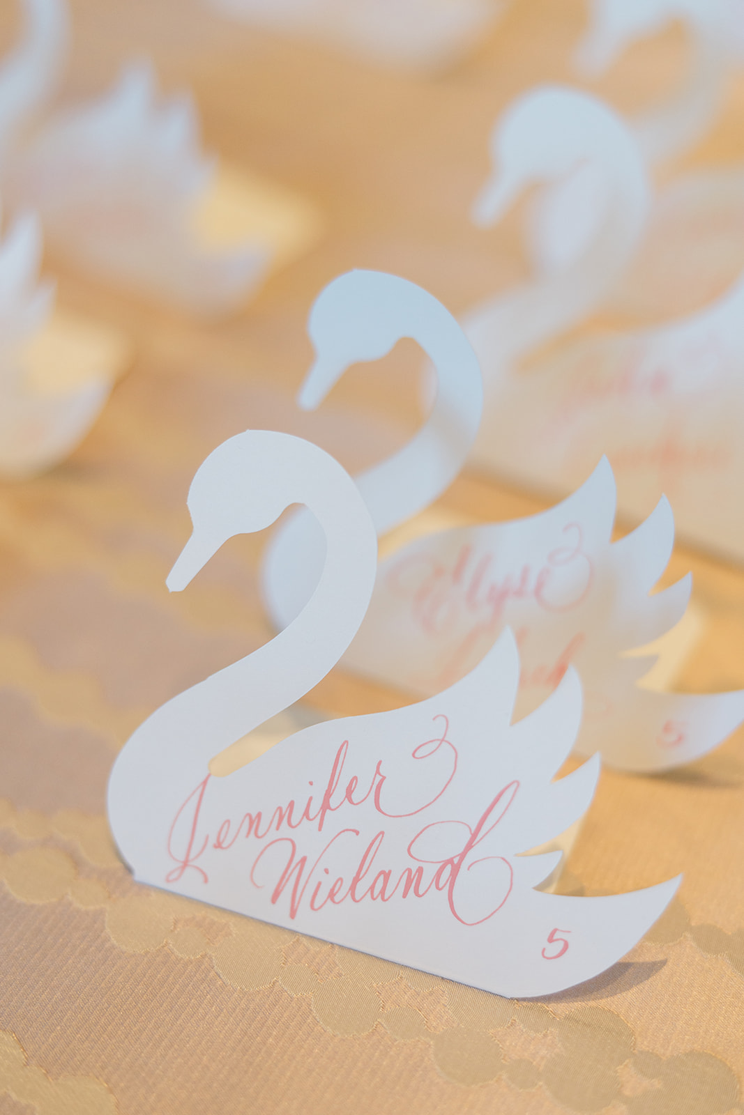 die-cut swan escort cards with pink calligraphy